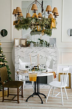 Stylish Scandinavian interior of the dining room with a Christmas tree. Various chairs near the round table. Classic modern home