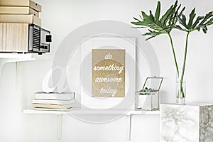 Stylish scandinavian interior with white shelf, white mock up poster frame, suculent in glass box, leaf in vase, papet boxes.