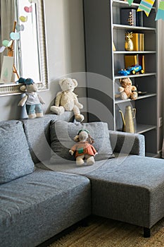 Stylish scandinavian nursery interior with shelves teddy bear and toys. Hanging flags cozy and sunny child room