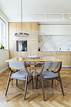 Stylish scandinavian open space interior of kitchen and dining room with design family table and chairs and other kitchen.