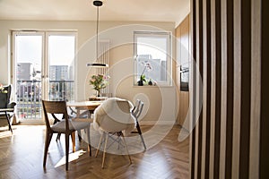 Stylish scandinavian open space interior of kitchen and dining room with design family table and chairs and other kitchen.