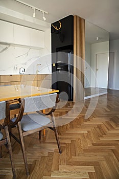 Stylish scandinavian open space interior of kitchen and dining room with design family table and chairs and other kitchen.