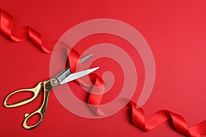 Stylish scissors and red ribbon on color background, flat lay. Ceremonial tape cutting