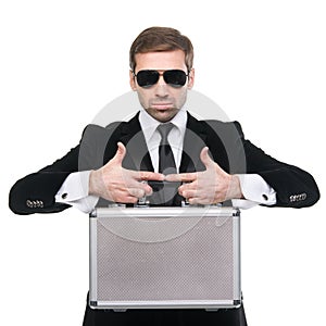 Stylish security guard holds metal suitcase.