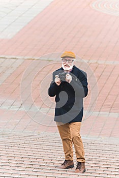 stylish senior man with photo camera standing