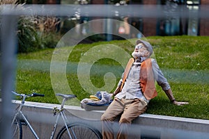 Stylish senior man sitting in the city park, enjoying warm weather. City commuter riding bike.