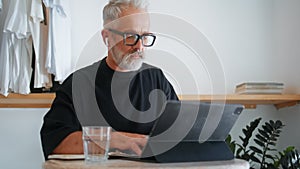 Stylish senior using tablet computer closeup. Thoughtful businessman browsing