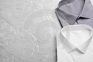 Stylish shirts on grey table, flat lay with space for text. Dry-cleaning service