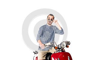Stylish shocked young man sitting on red scooter  on white