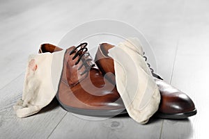 Stylish shoes with dirty socks on white wooden floor indoors, closeup