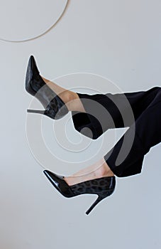 Stylish slim women feet in black high heels. Female legs in pants on white background. Elegant shoes fashion for woman