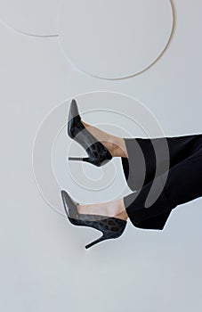 Stylish slim women feet in black high heels. Female legs in pants on white background. Elegant shoes fashion for woman