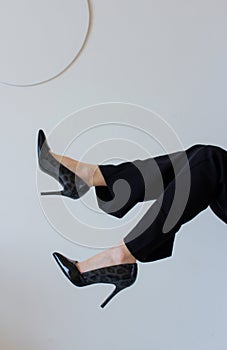 Stylish slim women feet in black high heels. Female legs in pants on white background. Elegant shoes fashion for woman