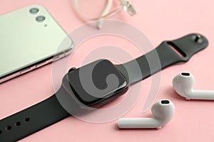 Stylish smart watch, phone and earphones on pink background