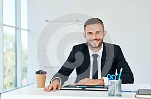 Stylish smiling businessman in elegant suit sitting at his desk in a bright modern office