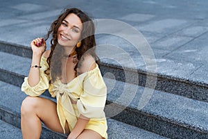 Stylish smiling woman in public area sitting on stairs