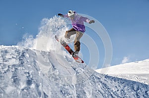 Stylish snowboarder with helmet and mask jumps from high snow slope