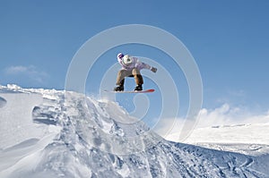 Stylish snowboarder with helmet and mask jumps from high snow slope