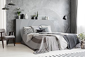 Stylish standing lamp next to a bed in a monochromatic grey bedr