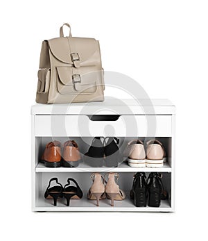 Stylish storage cabinet with different pairs of shoes and backpack on white background