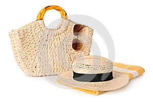 Stylish straw hat, beach bag, towel and sunglasses on white background