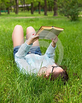 Stylish student girl relax with book in beautiful summer park at sunny day. Outdoor lifestyle picture