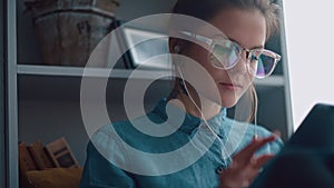 Stylish student girl sits by the window and reads an e-book