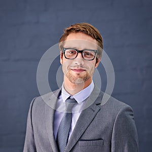 Stylish and successful. Portrait of a handsome young businessman standing against a gray background.
