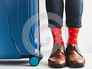 Stylish suitcase, men`s legs and bright socks