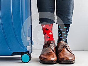 Stylish suitcase, men`s legs and bright socks