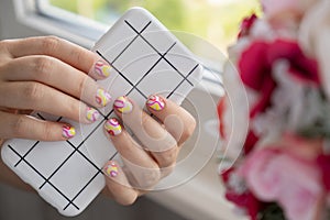 Stylish summer colorful nails female manicured hands holding mobile phone. Closeup of manicured nails of woman hand