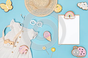Stylish summer set of child clothes. White blank card, cotton dress, straw hat, sunglasses and funny gingerbread on yellow