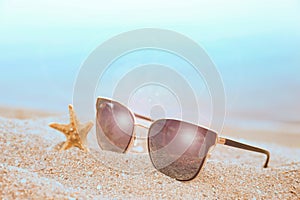 Stylish sunglasses and starfish on sandy beach