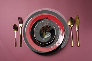 Stylish table setting with cutlery and floral decor on pink background, flat lay