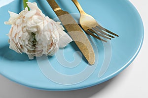Stylish table setting with cutlery and flower on white background, closeup