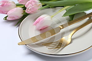Stylish table setting with cutlery and tulips on white background, closeup