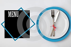 Stylish table setting and empty menu on background, top view. Space for text