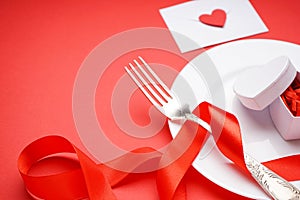 Stylish table setting and gift for Valentine`s Day on a red background, space for text, close-up