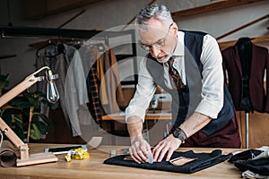 stylish tailor marking cloth pattern with chalk