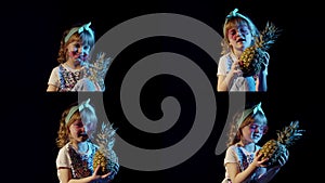 Stylish teen caucasian kid girl with pineapple standing on black background singing, fooling around