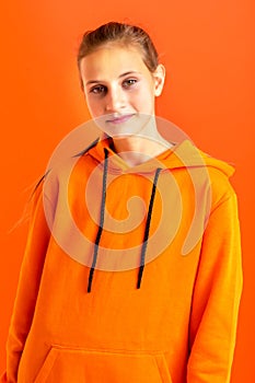 Stylish teenage girl in orange hoodie. Photo session in the studio