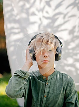 stylish teenager boy listening to music with headphones outdoors. youth movement. adolescence