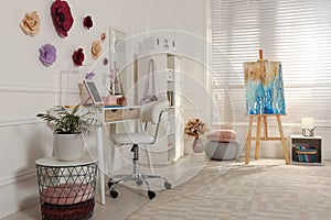 Stylish teenager`s room interior with computer and painting easel