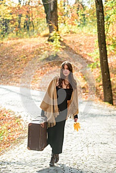 Stylish traveler, autumn woman. Full length of a sensual woman wearing a sweater walking with a travel bag over autumnal