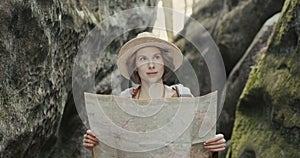 Stylish traveler girl in hat looking at map, exploring woods