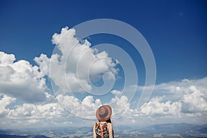 Stylish traveler woman in hat looking at sky and mountains. hips