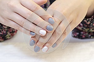 Stylish trendy female manicure. Beautiful young womans hands. gray and white nail