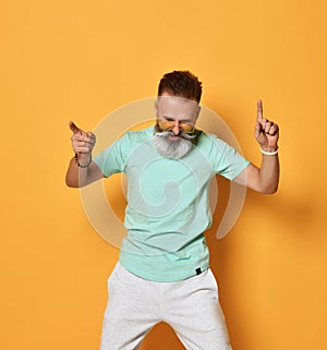 Stylish trendy gray-haired hipster guy dancing and having fun on bright orange background.