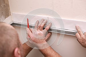 Stylish trendy white ceramic tiles on the kitchen wall. Hands in the process of laying white rectangular tiles on the