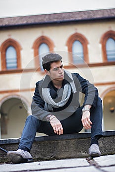 Stylish trendy young man sitting outdoor in old historical building